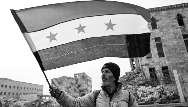 Un homme brandit un drapeau de l'opposition syrienne à la citadelle d'Alep, le 11 décembre 2024. Les rebelles islamistes ont pris la ville le 30 novembre.