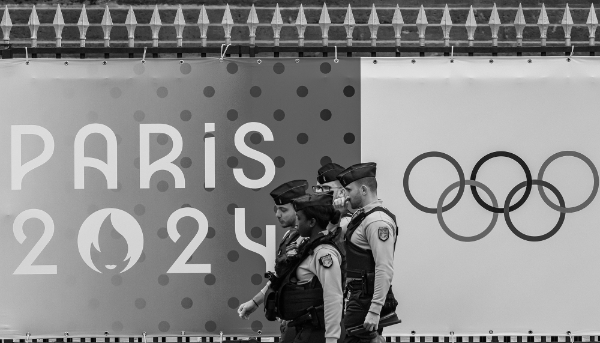 Des policiers passent devant une banderole des Jeux olympiques devant l'Assemblée nationale à Paris.